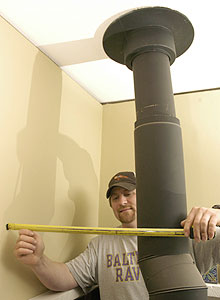 A man measures the distance between a wall and a chimney