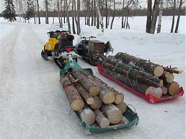 Towing out sled loads of firewood with snowmachines